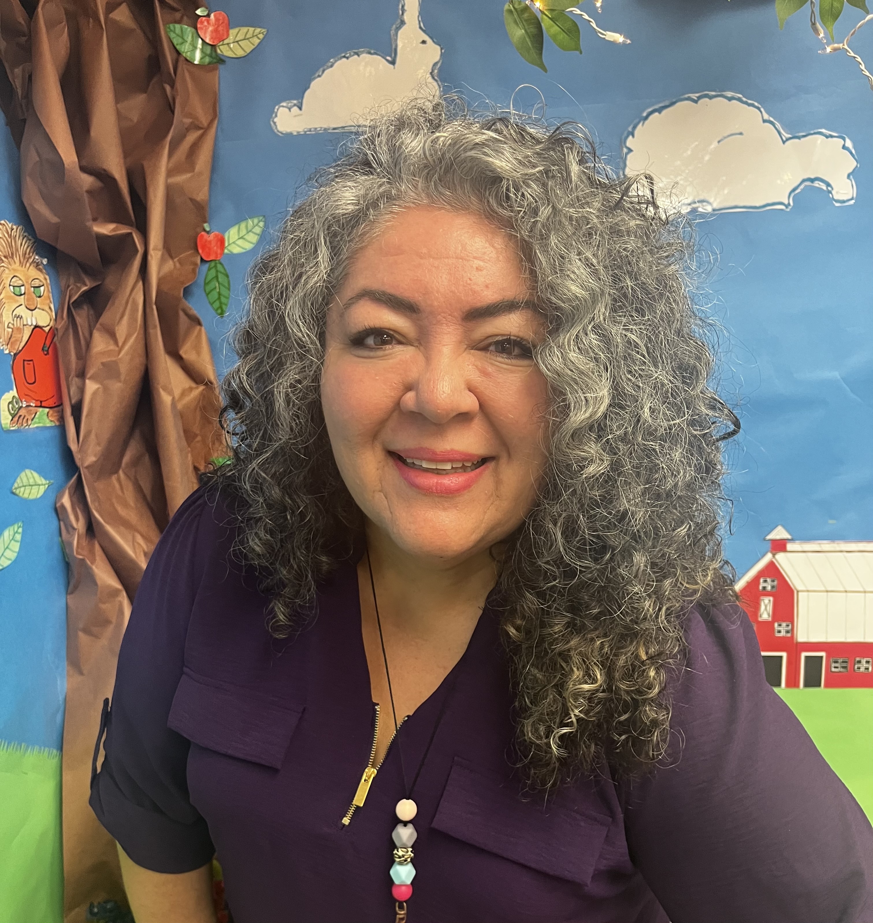 Ms. Astrid sitting for a portrait in front of a decorated wall