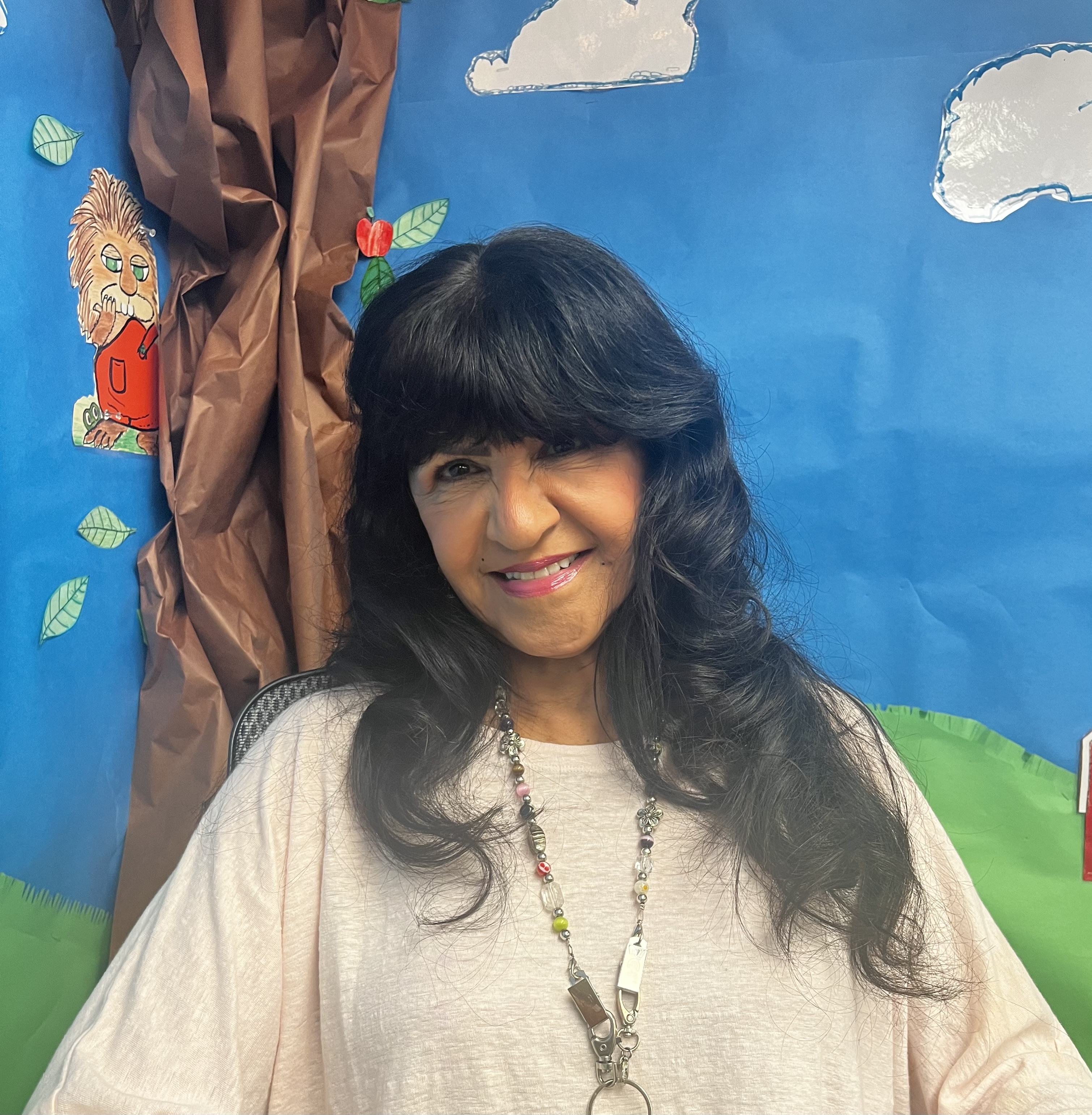 Teacher posing for a portrait in front of a decorated wall