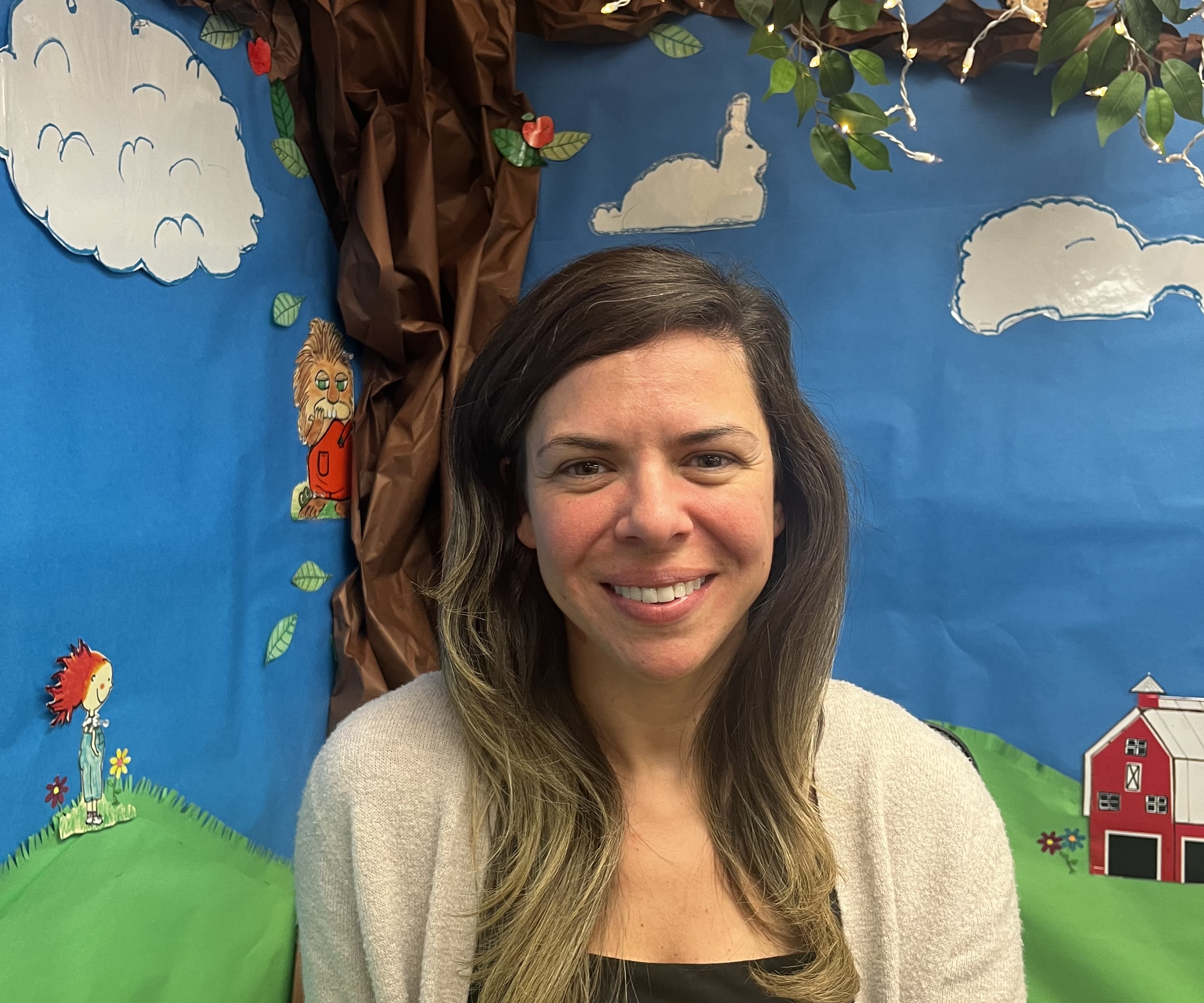 teacher posing for a portrait in front of a decorated wall