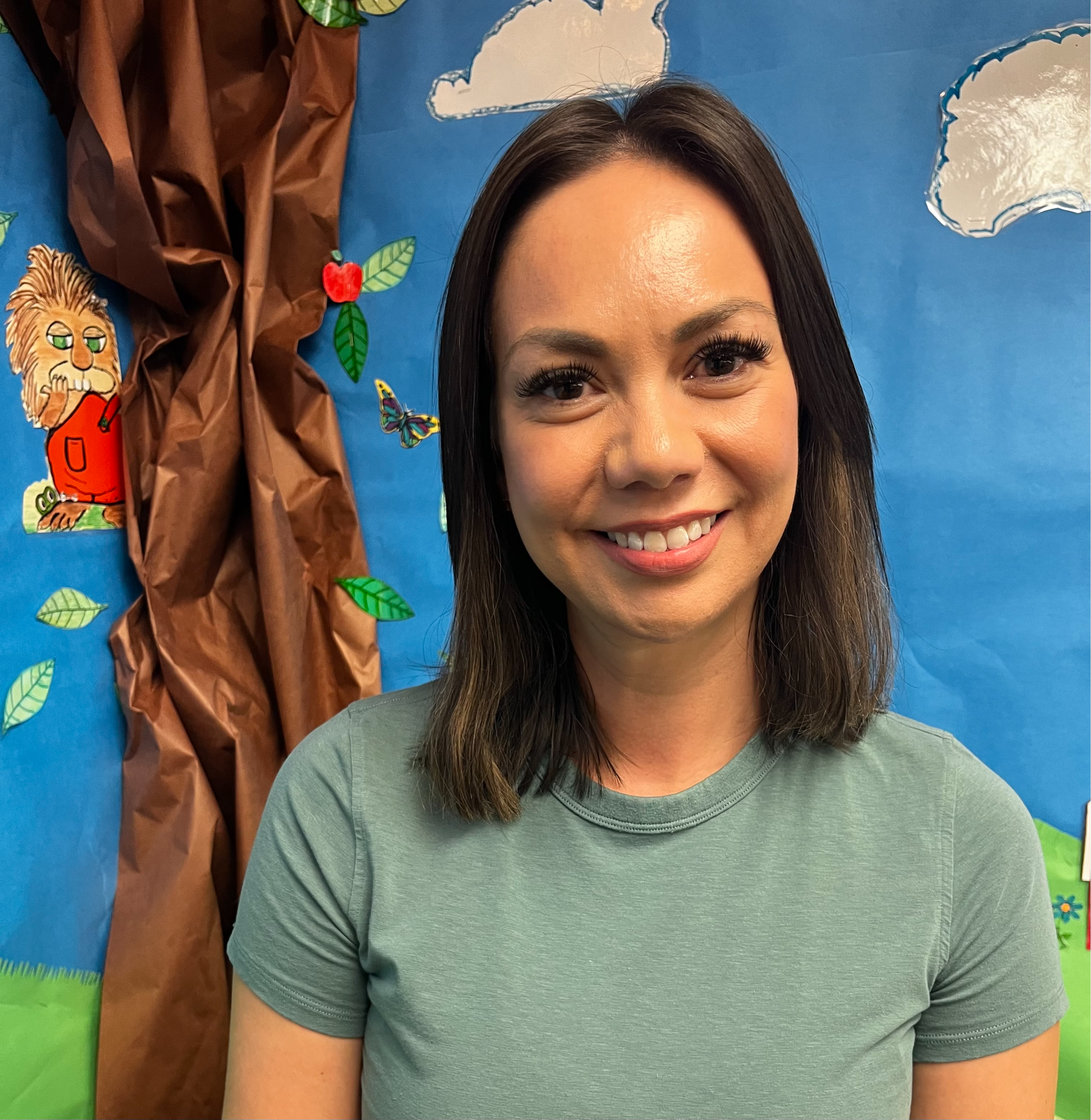 Ms. Jess sitting for a portrait in front of a decorated wall