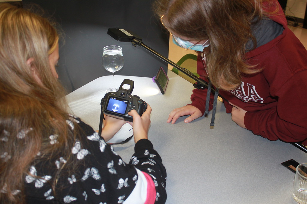 Students in photography class looking at photo on camera