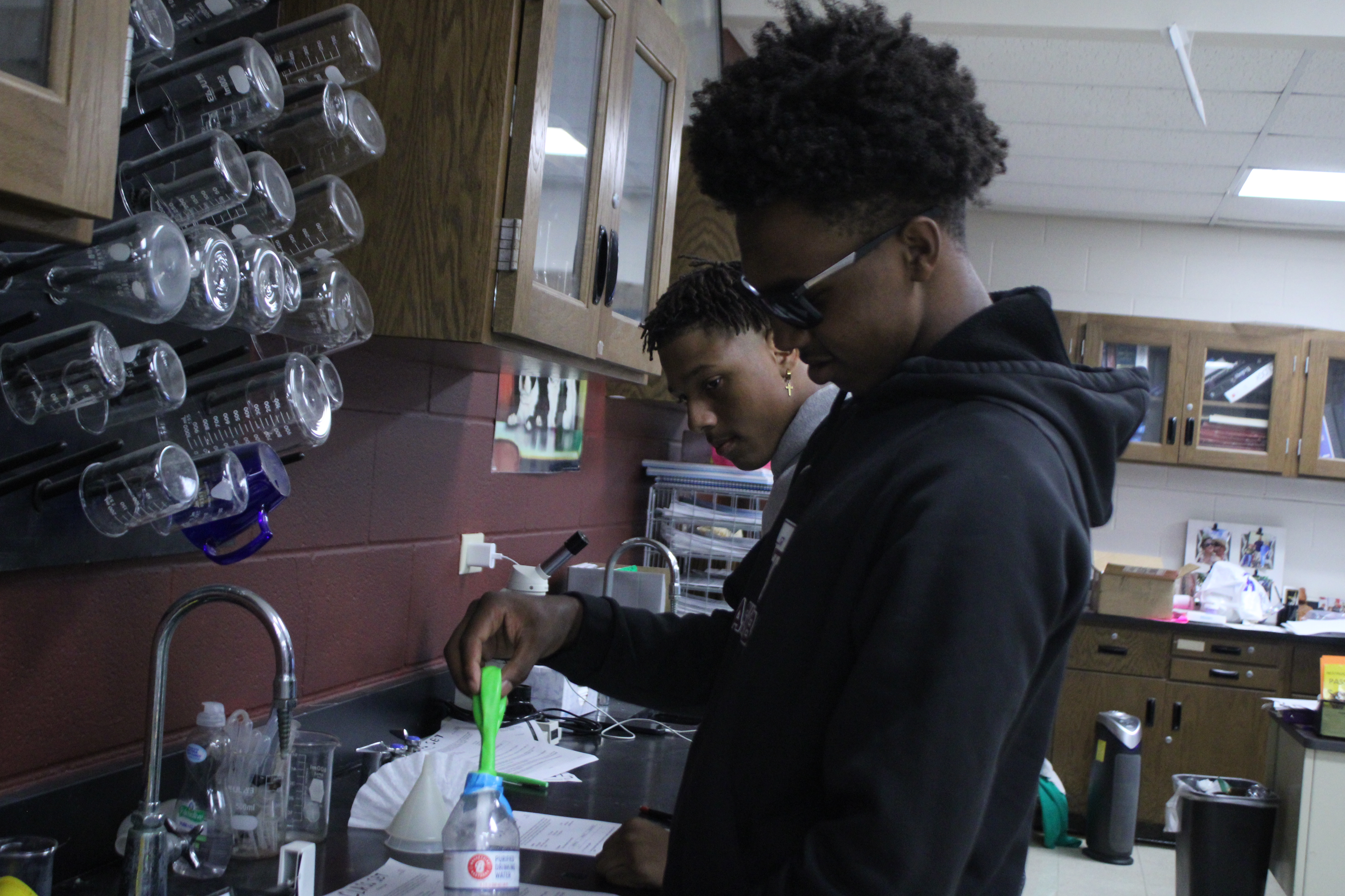 Two students working on a baking soda and vinegar chemistry experiment.