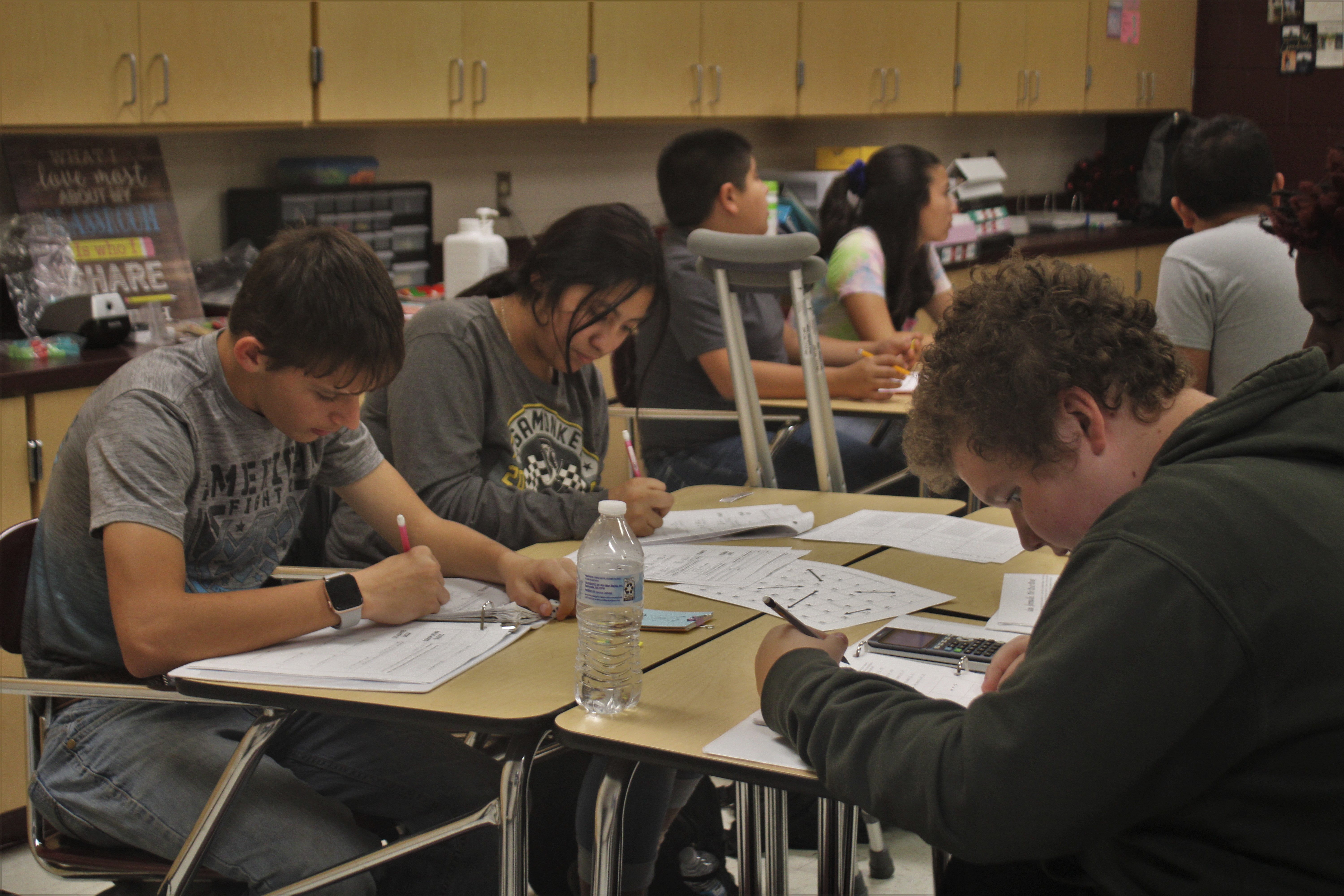 Three students sitting in math class working on their assignment.