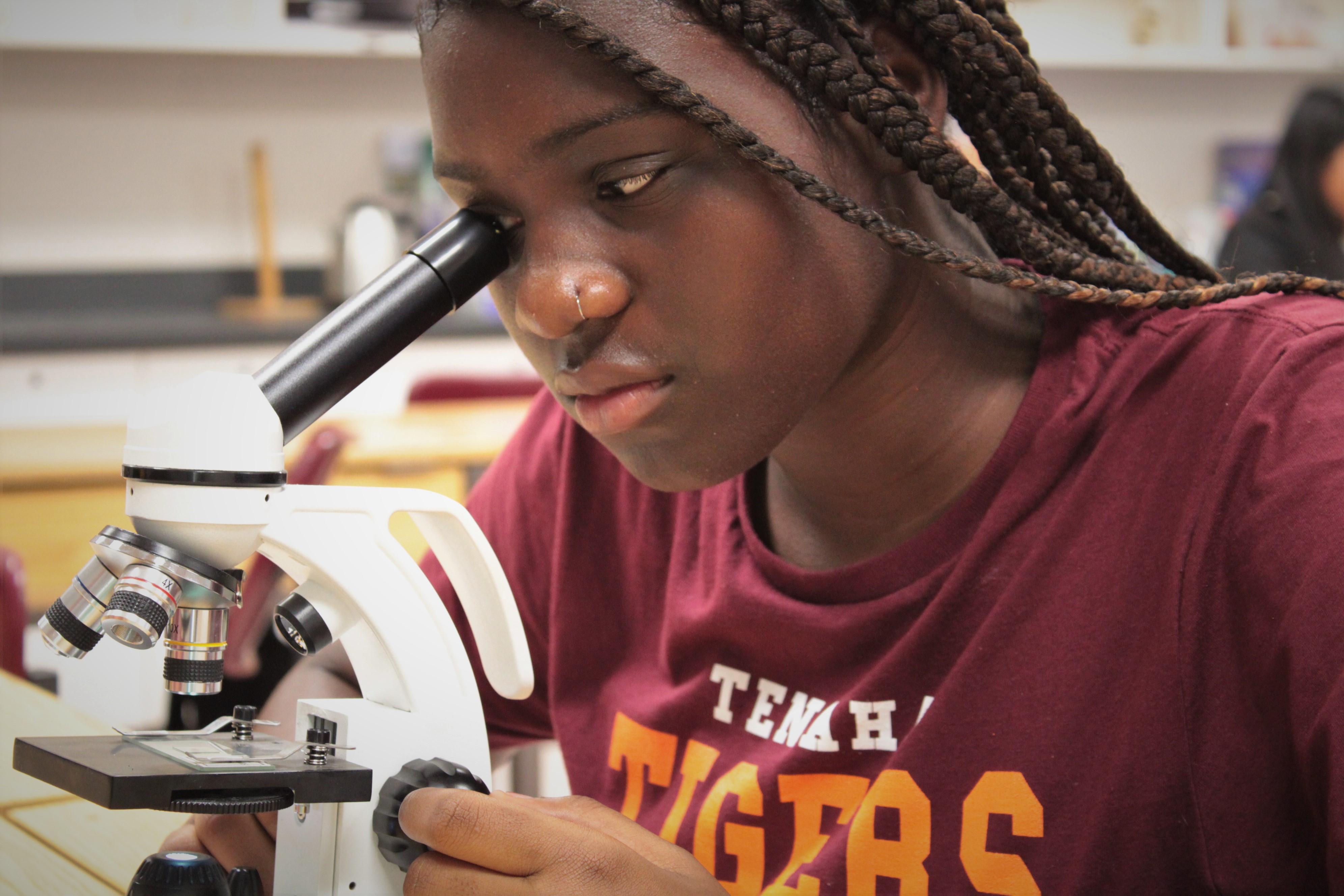 A middle school student looking into a microscope.