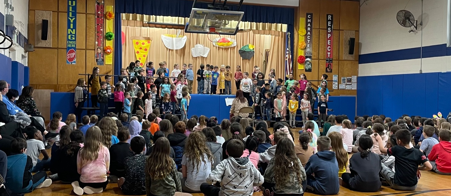 Lillian Drive students standing on a stage performing in front of an audience 