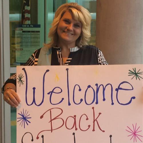 teacher holding sign that says welcome back students