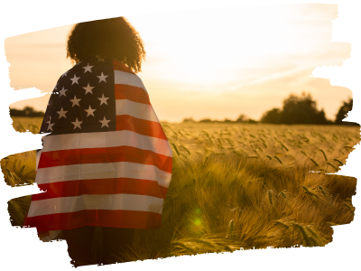 Girl with American flag standing in wheat field