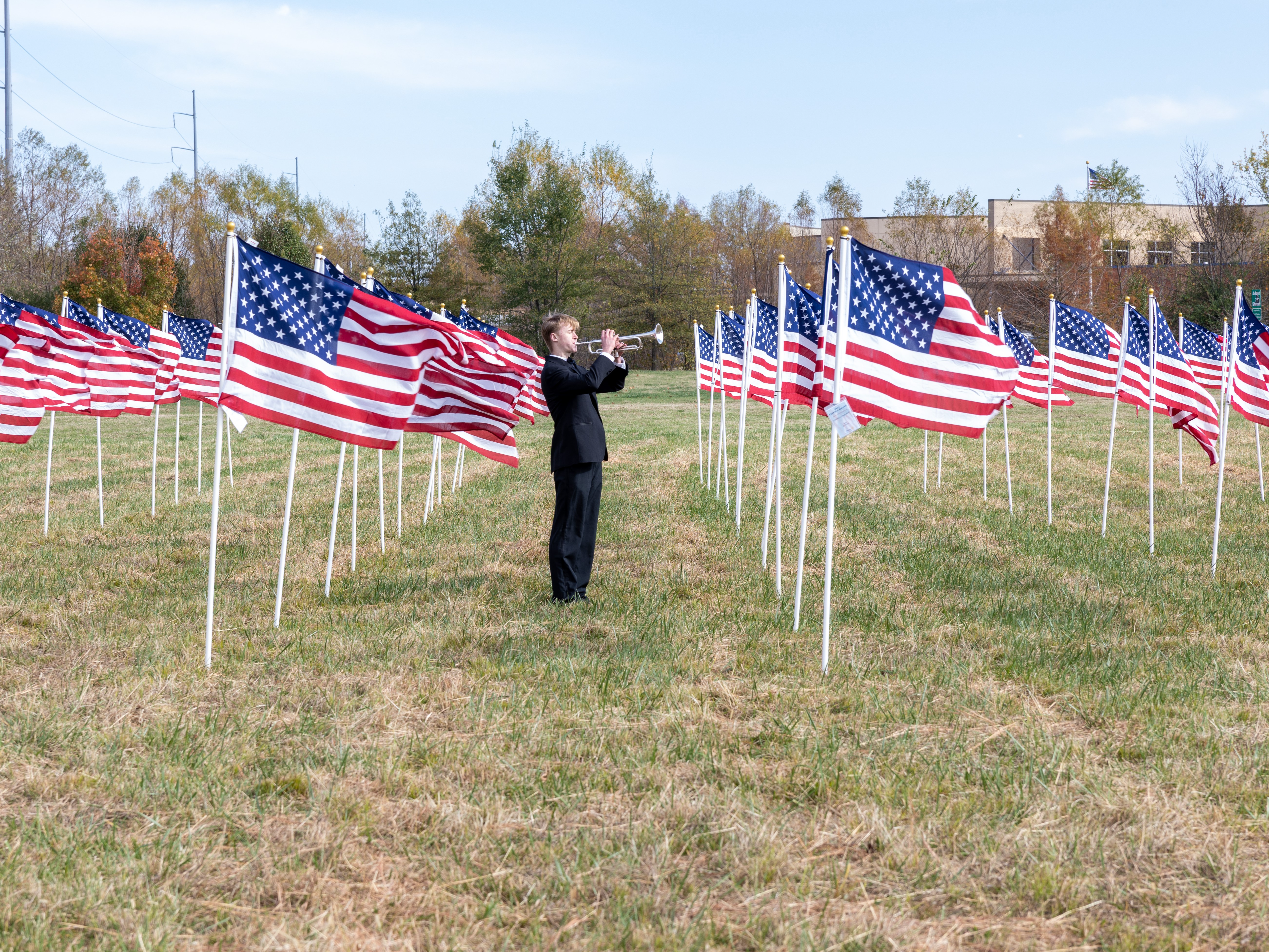 Student playing the trumpet in field of American flags