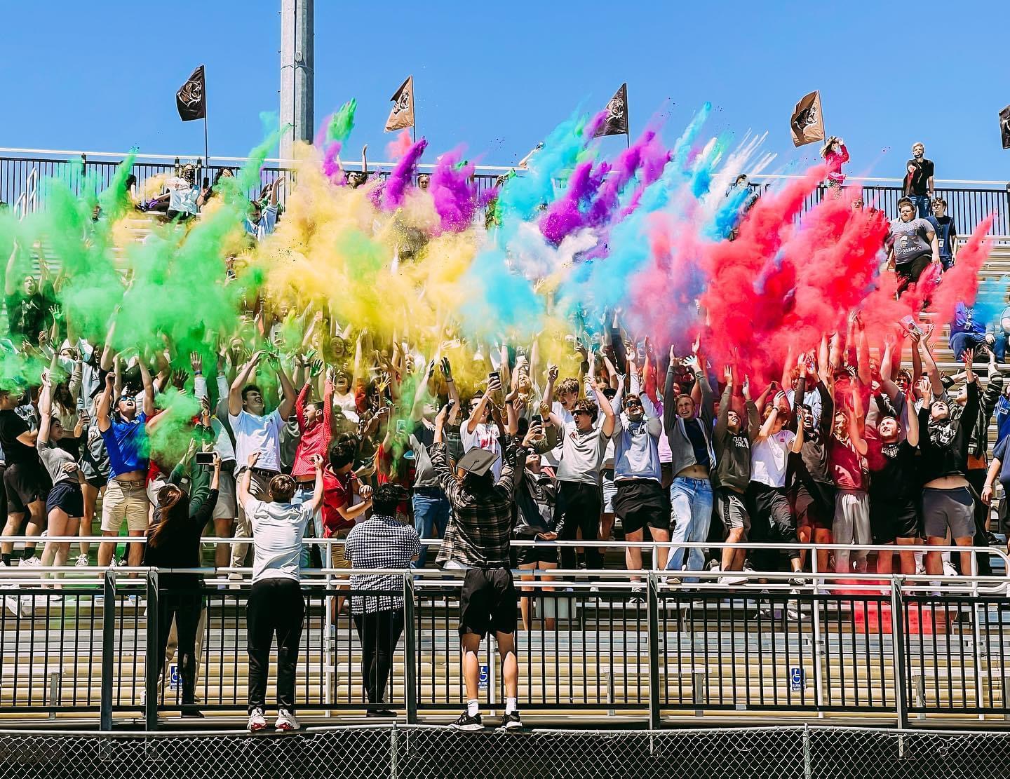 Students throwing colored chalk at a footbal stadium