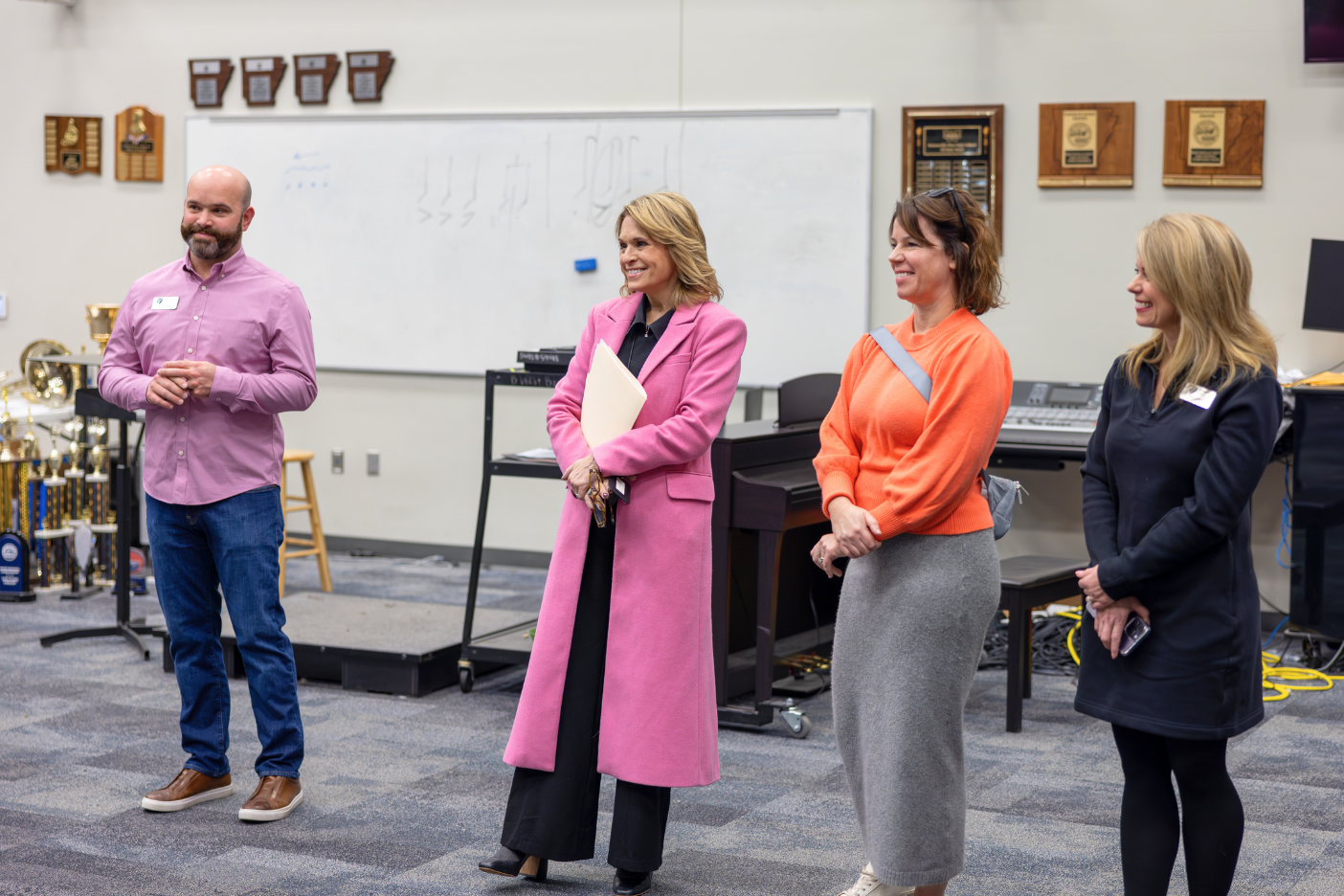 A man and three women  standing in a music classroom