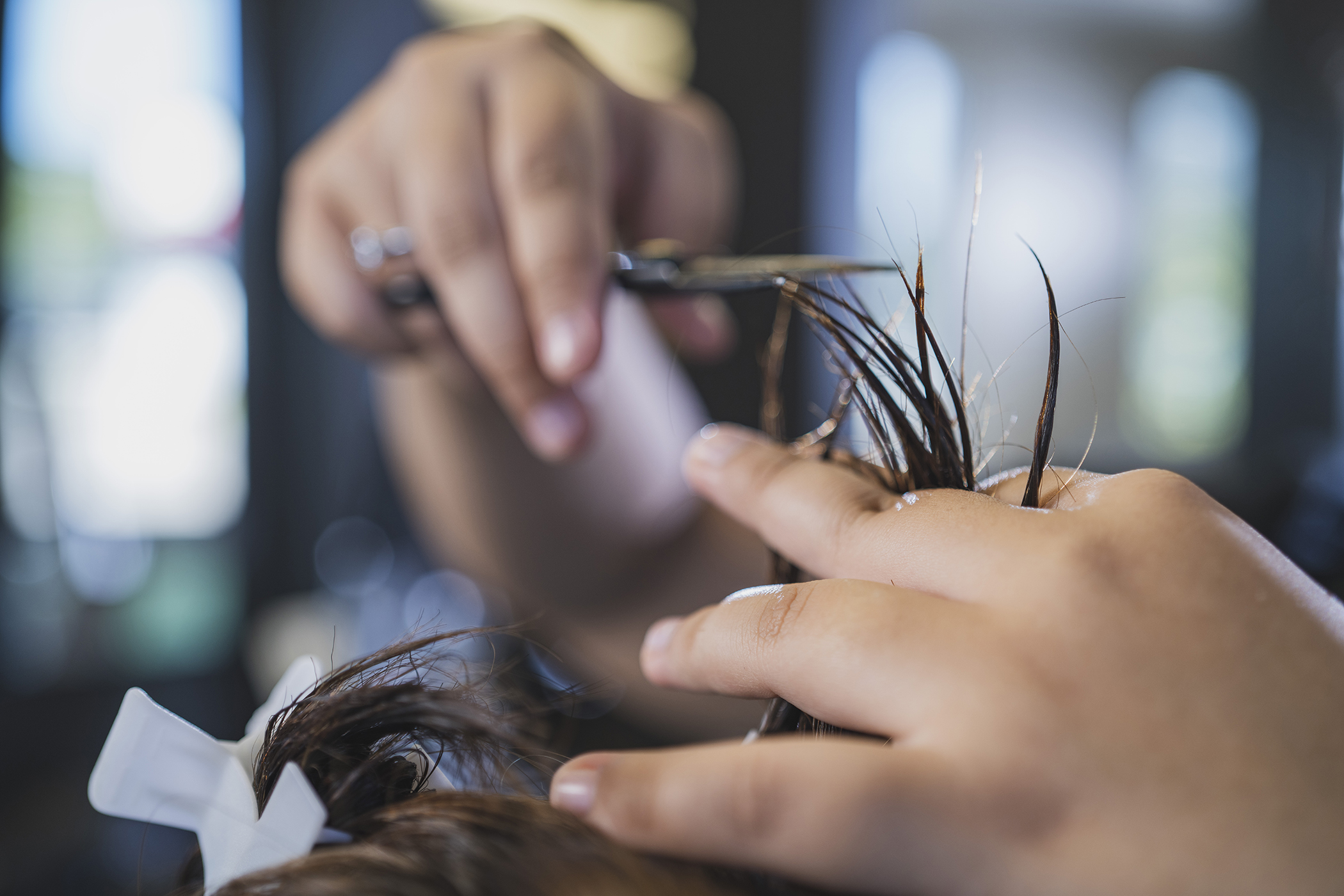 Woman's hands using scissors to cut hair 