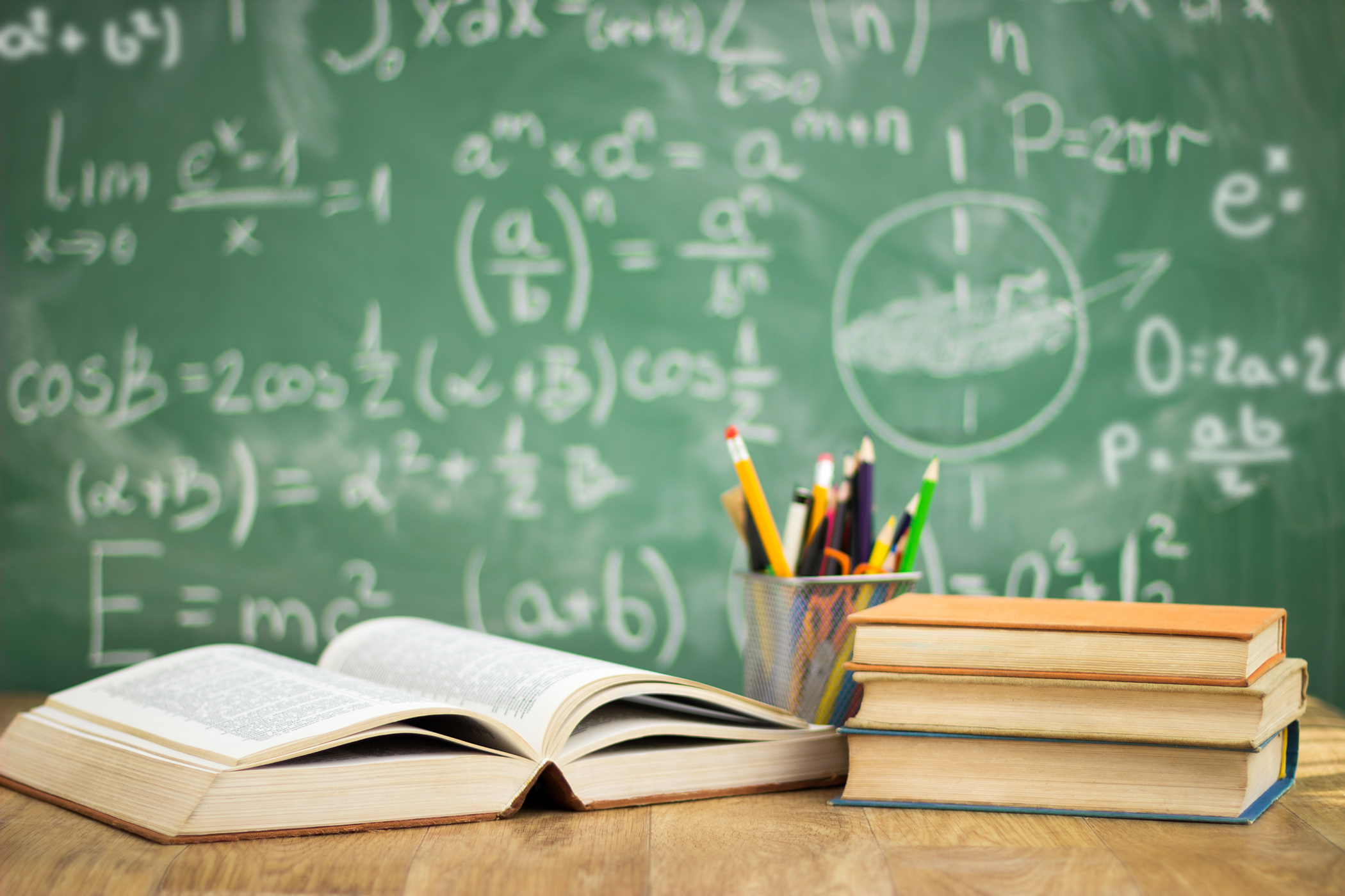 Chalk board background with books and pencils on desk