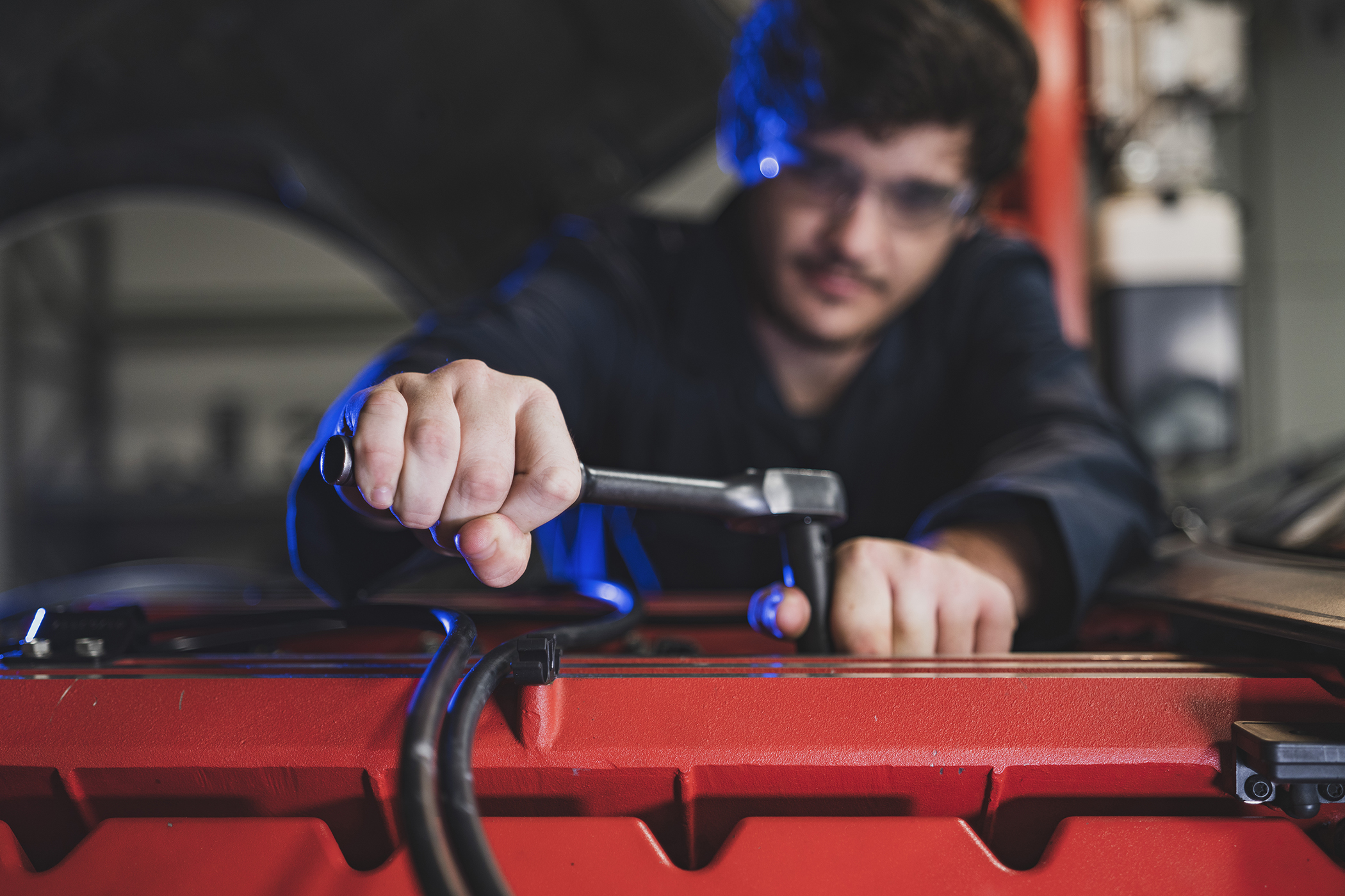 Man with wrench working on an automobile engine. 