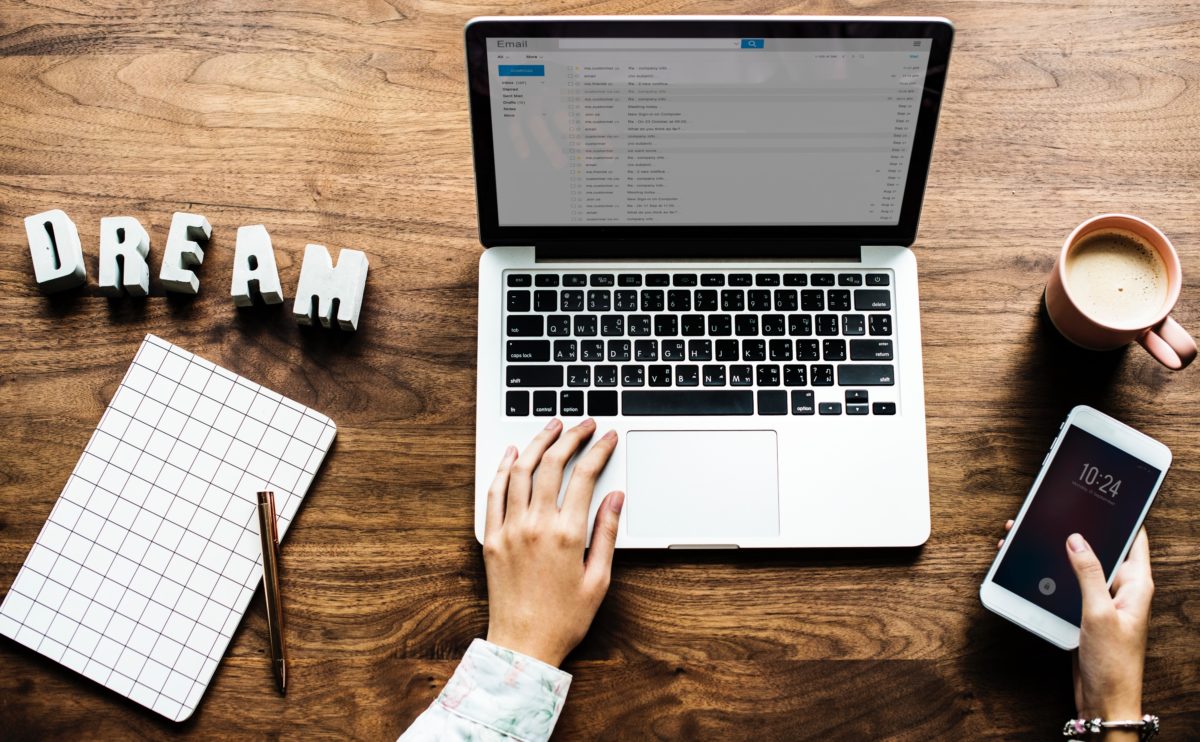 Desk with person at computer with coffee and "Dream" in the background.