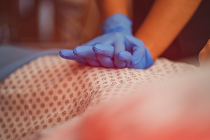hands wearing blue gloves performing cpr on torso