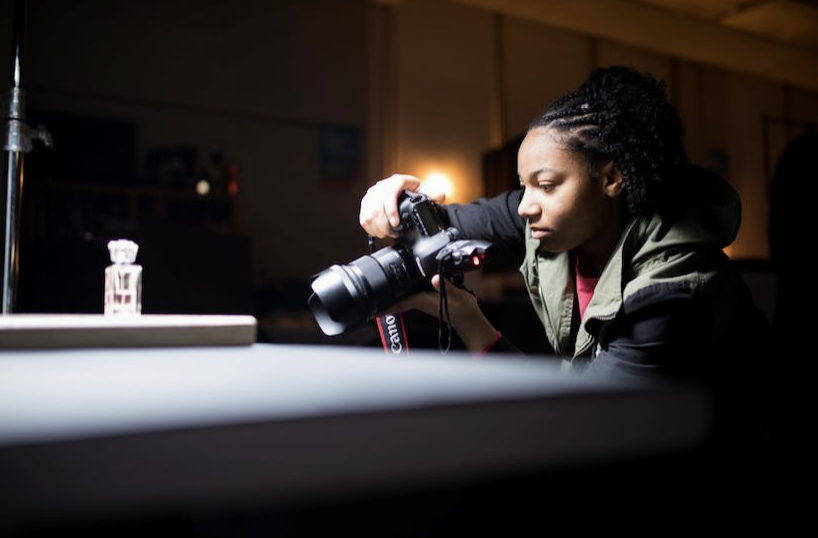 student taking close up photos of objects in dark room with shadows