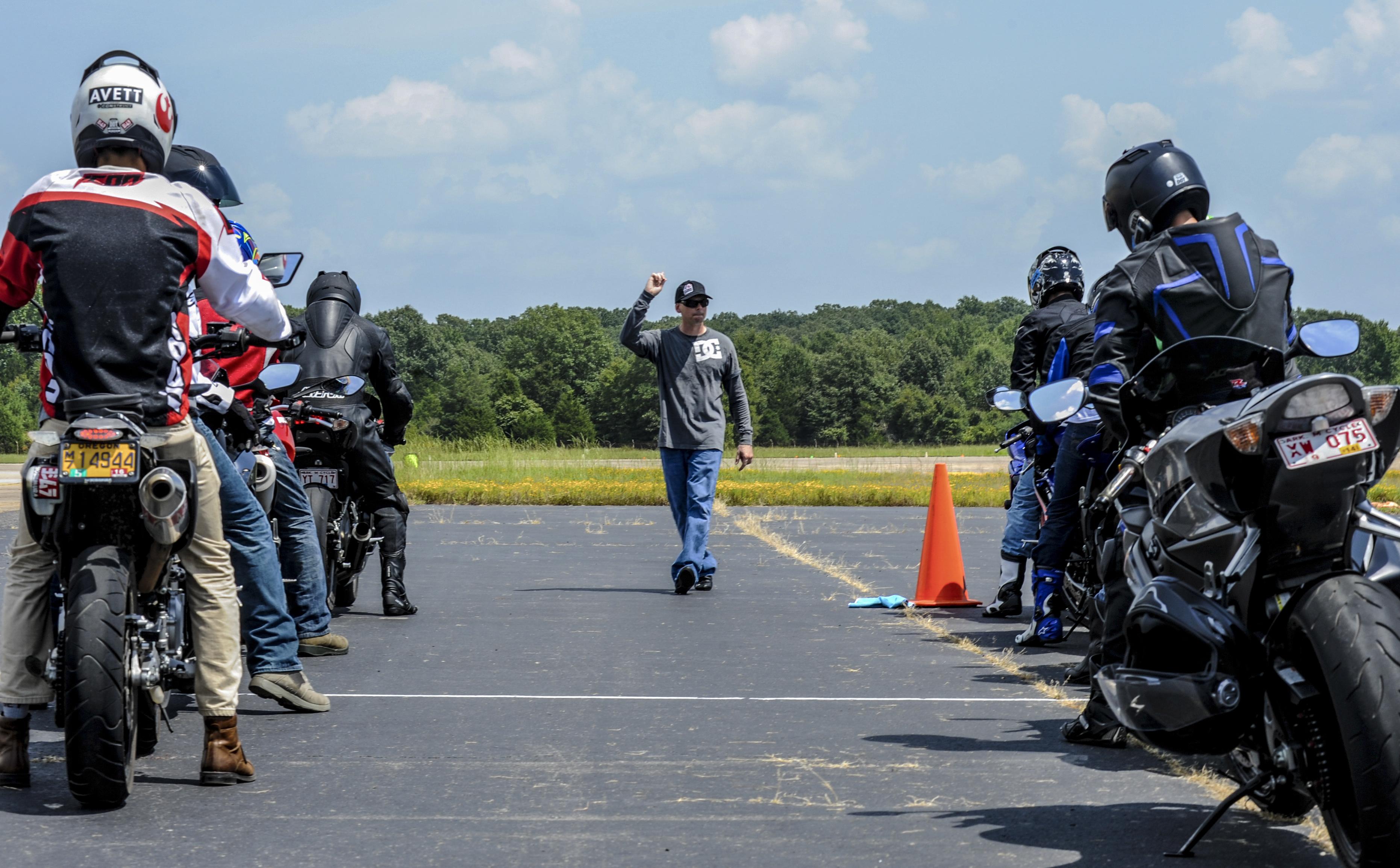 motorcycles and riders on street ready to take safety test with instructors in front giving direction