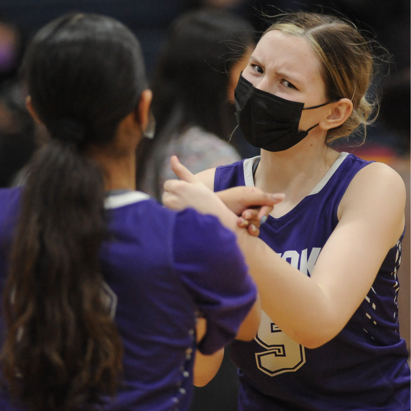 Two student athletes at a game facing each other wearing their purple knight jerseys.