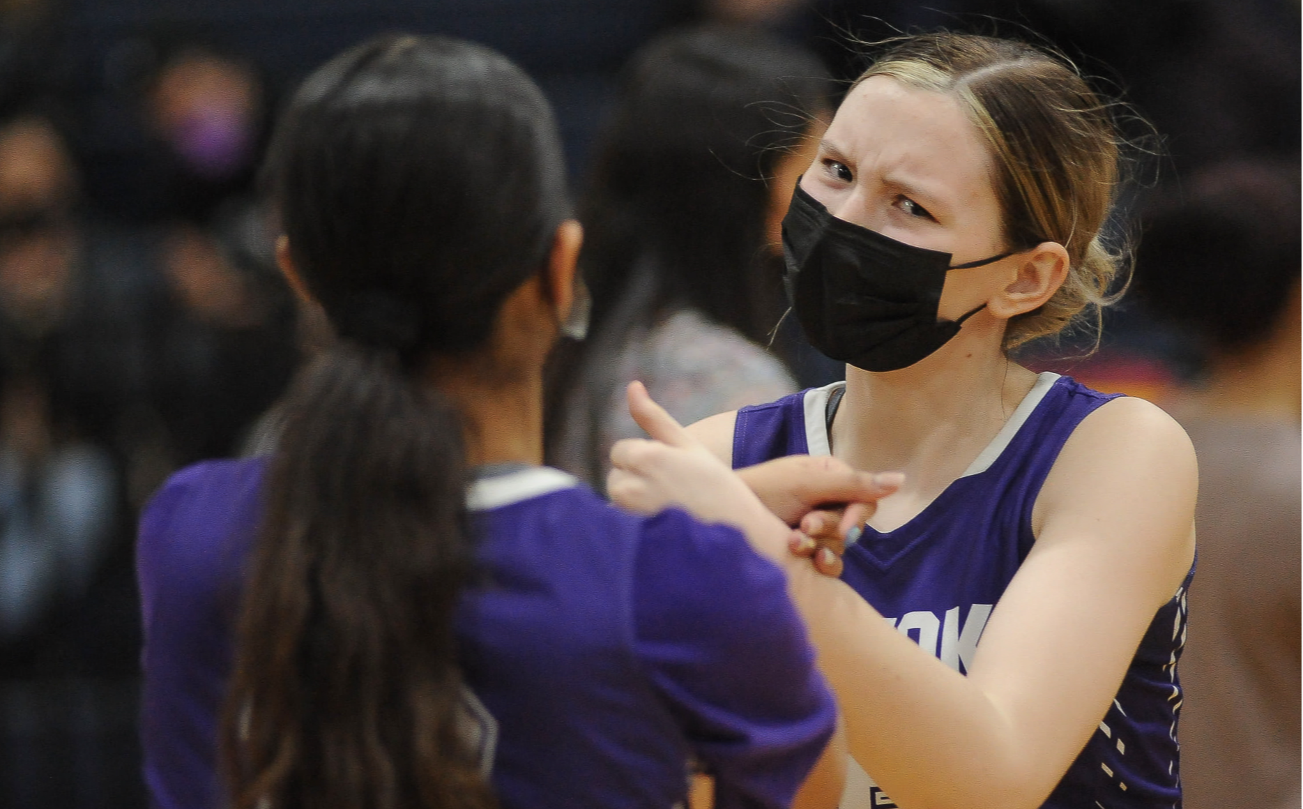 Two student athletes at a game facing each other wearing their purple knight jerseys.