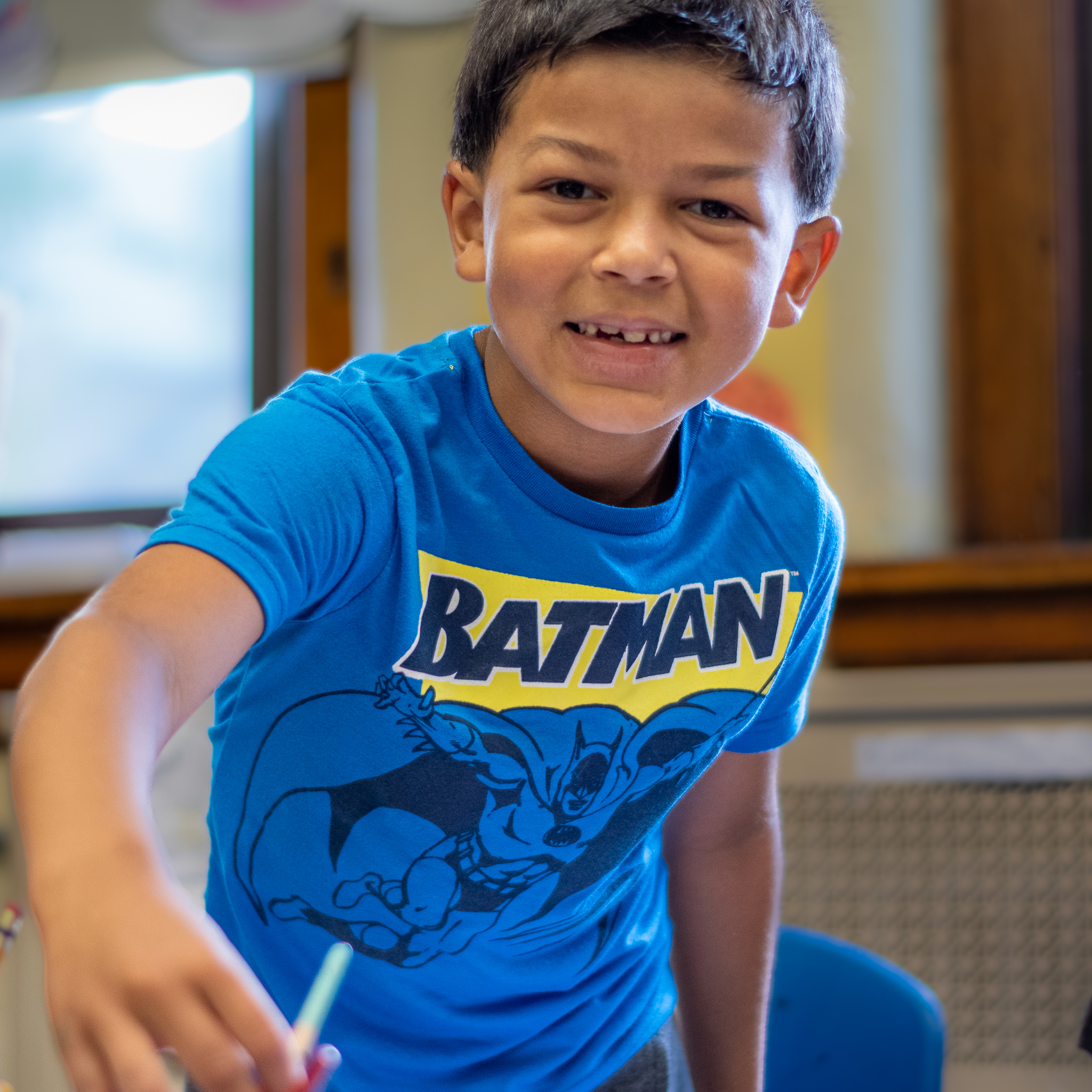 Student wearing a blue Batman shirt and holding a water color brush.