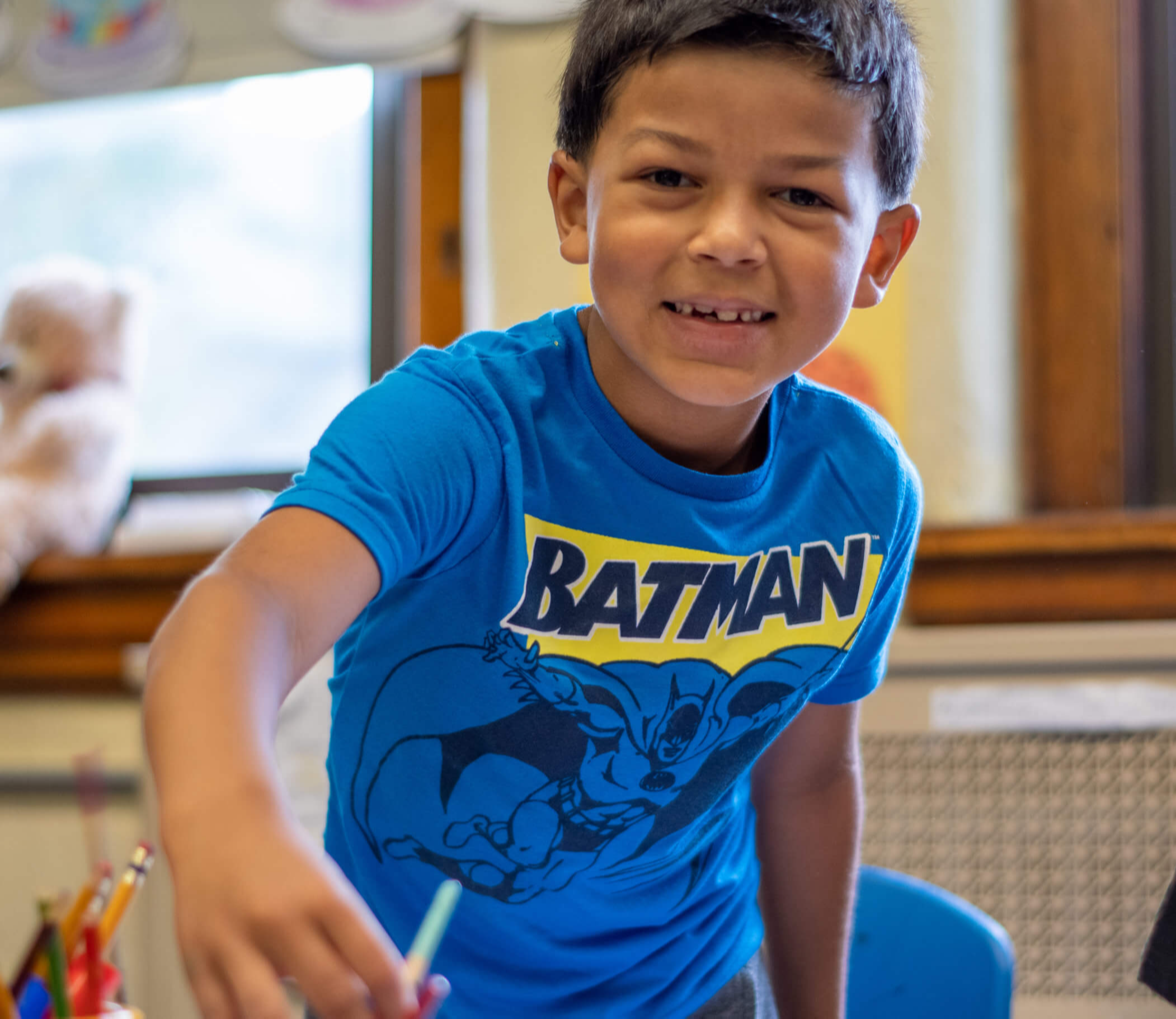 Student wearing a Batman blue shirt and holding a water color brush.