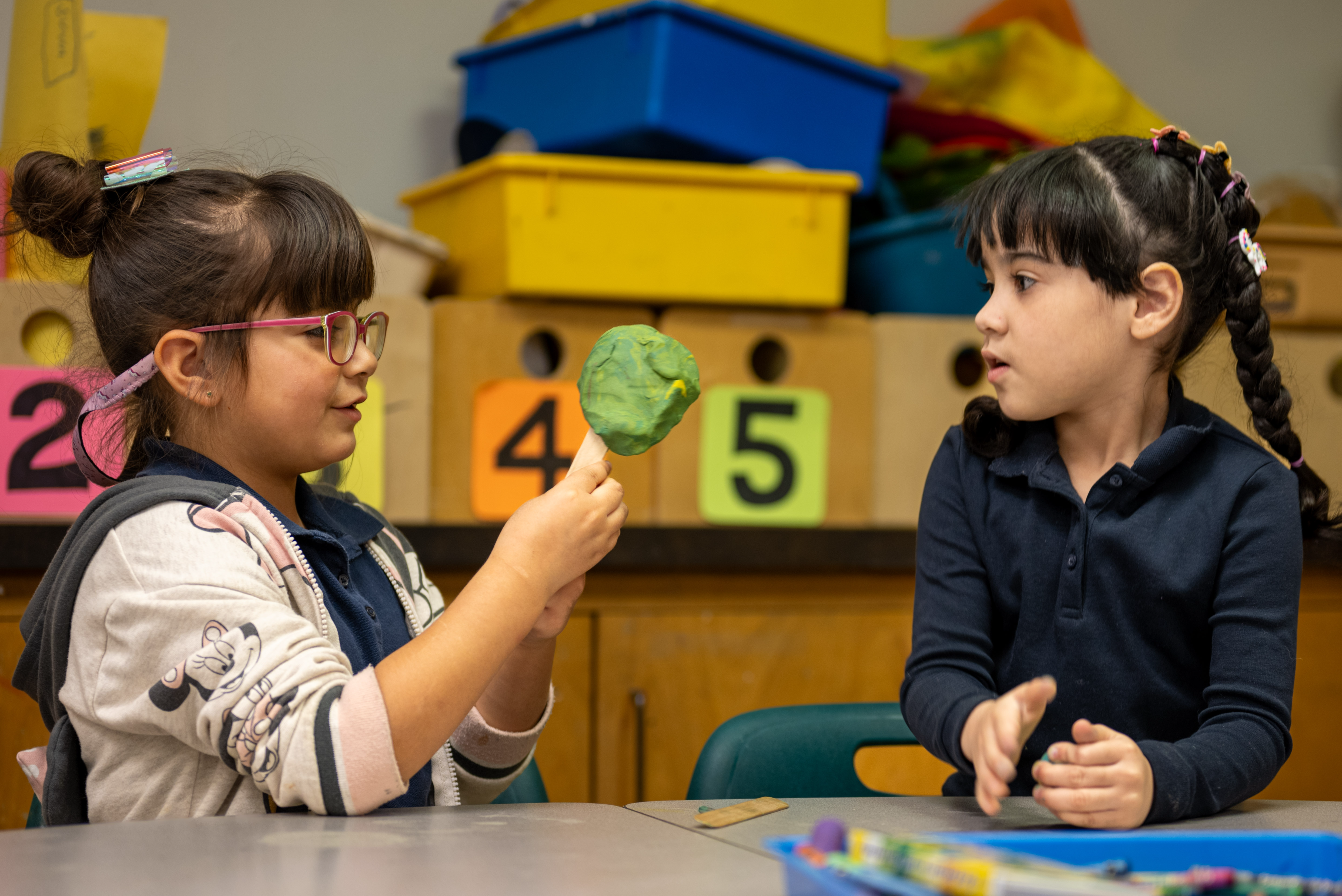 Two students in art class making shapes out of play dough.