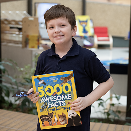 Student holding magazine that says 5,000 awesome facts (about animals!)
