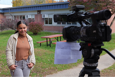 Student being interviewed in front of school with video camera recording