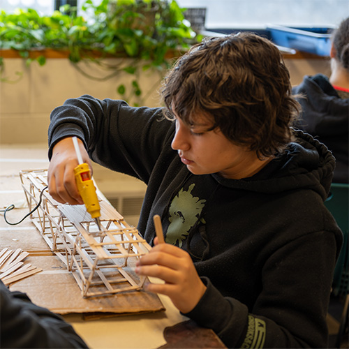 A student working with wooden sticks on a project 