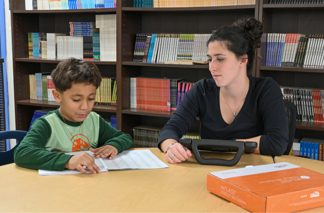 A student at Morgan School practices reading in the library with the guidance of a staff member