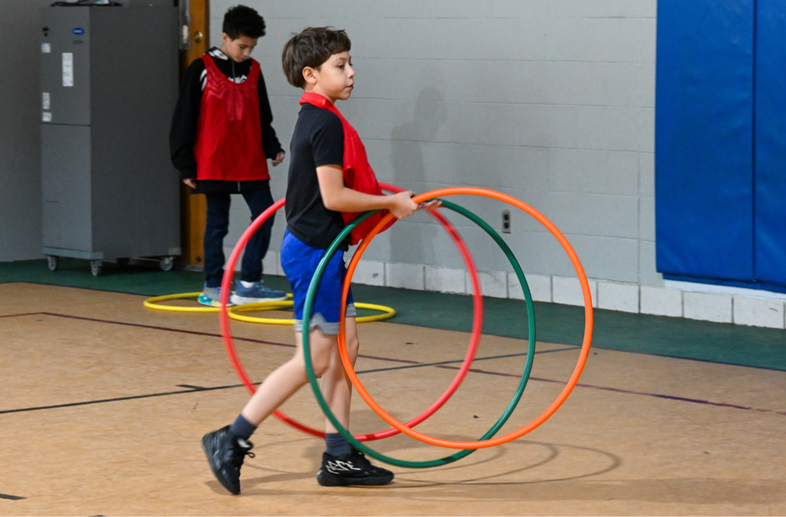 A Kelly School student uses hula hoops to prepare for a game in Physical Education