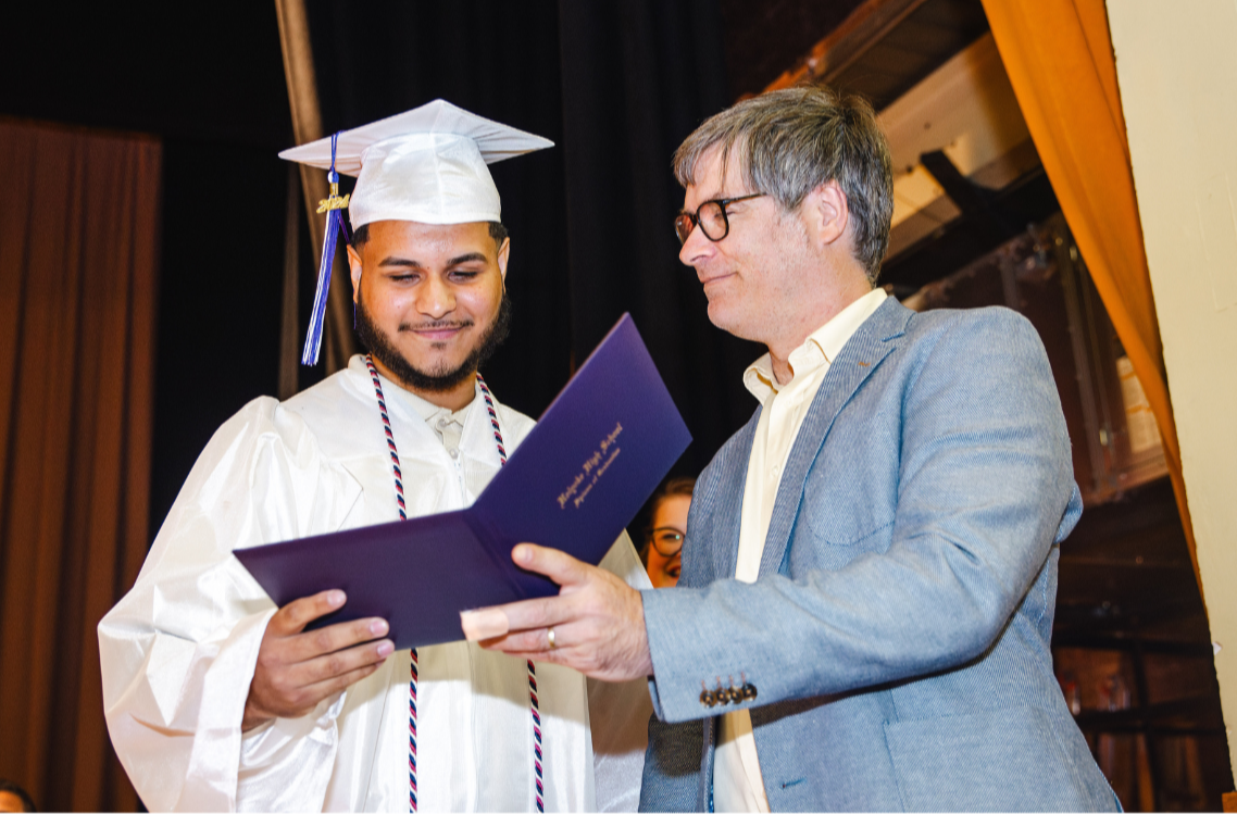 A graduating student from Opportunity Academy accepts his degree on stage