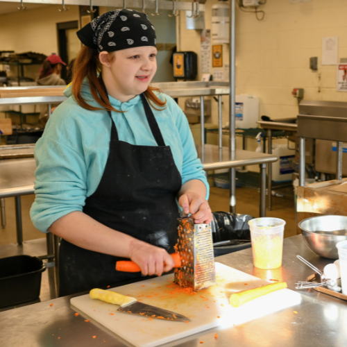 A culinary student shreds carrots