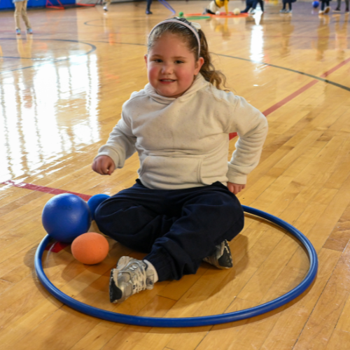 A Kelly student sits in  a hula hoop during physical education