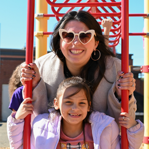 A teacher and student smile at the camera on the playground