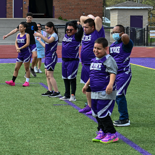 Two student athletes at a game facing each other wearing their purple knight jerseys.