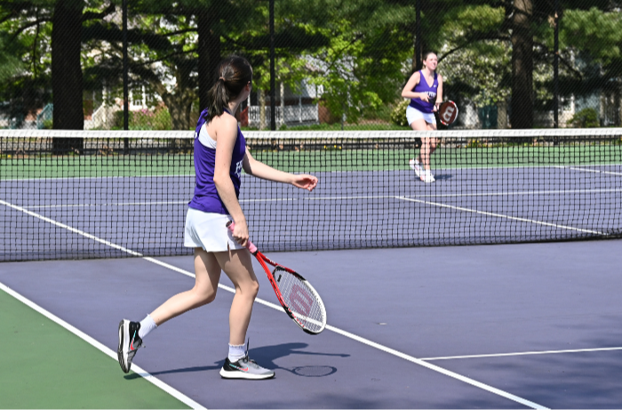 Two HHS tennis players warm up prior to a home match