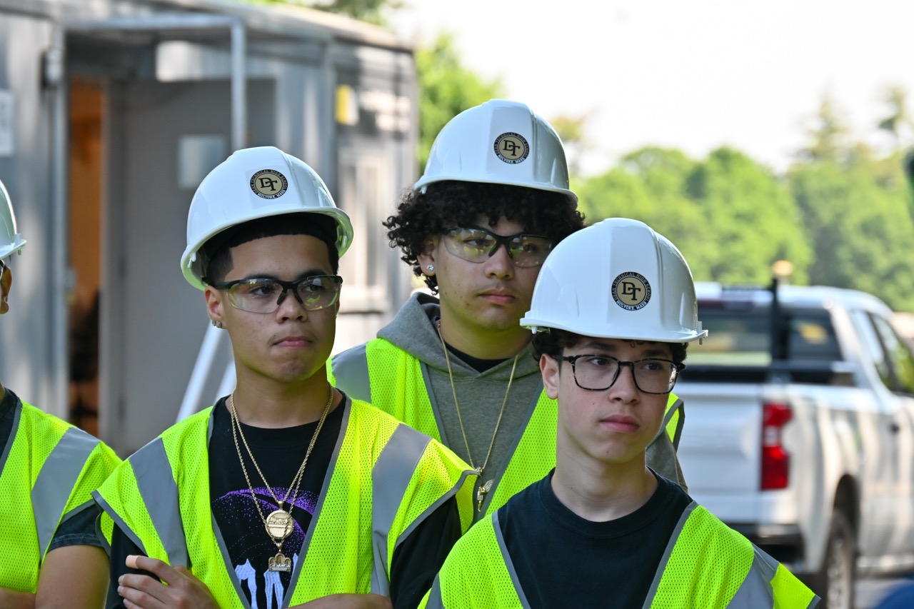 Three Dean students in hard hats look off camera