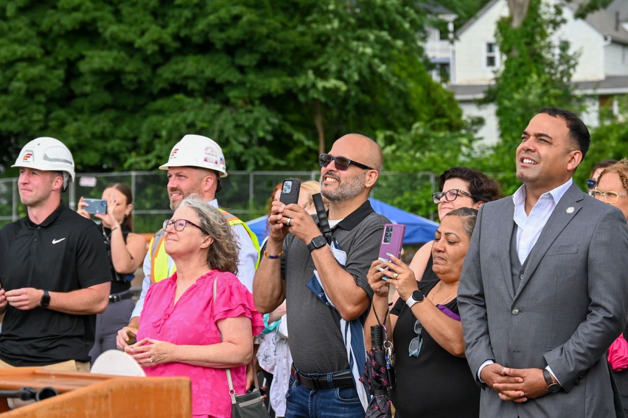 Representatives look up at the beam being placed