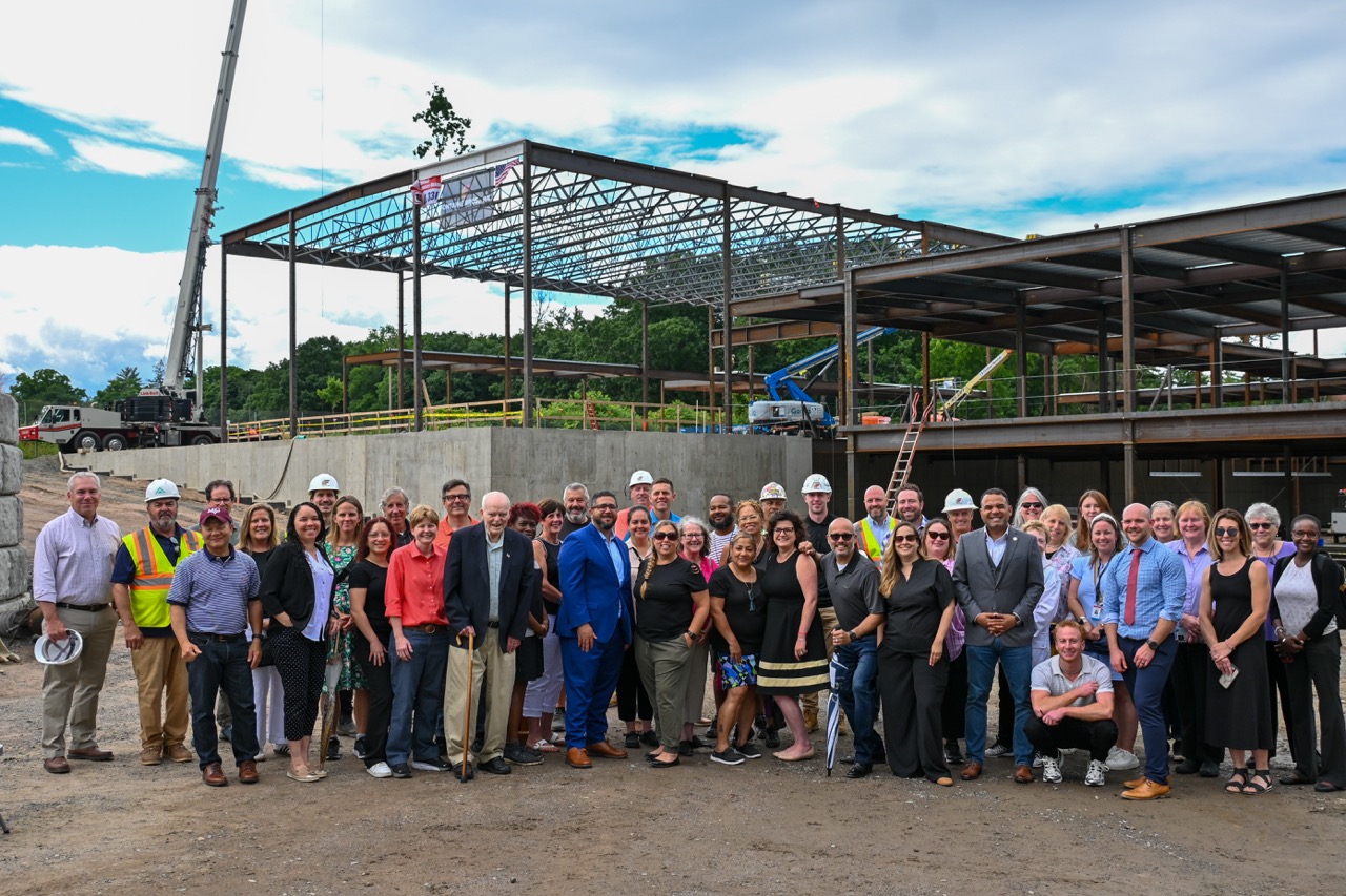 Guests pose in a group photo in front of the placed beam