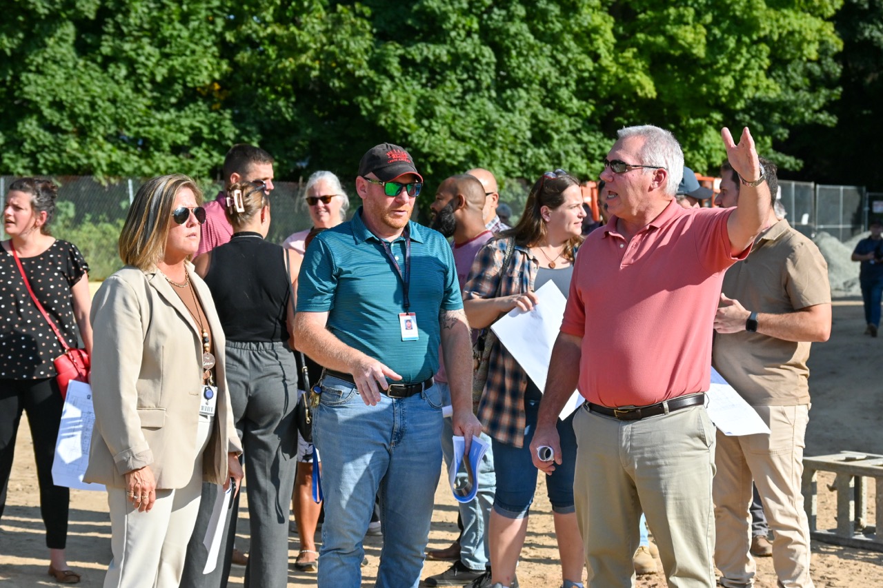 Project leaders point at the building and explain its features to listeners