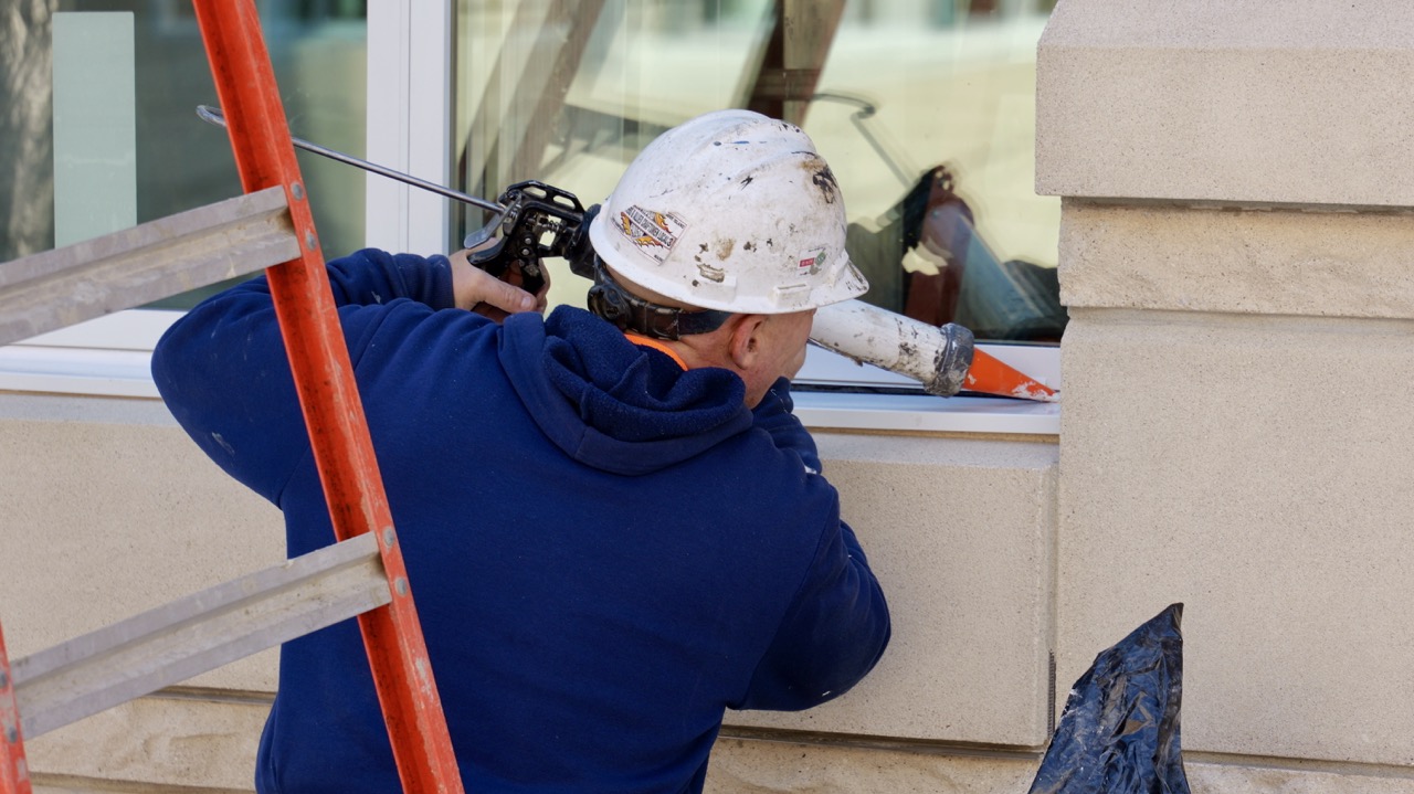 A worker caulks in windows