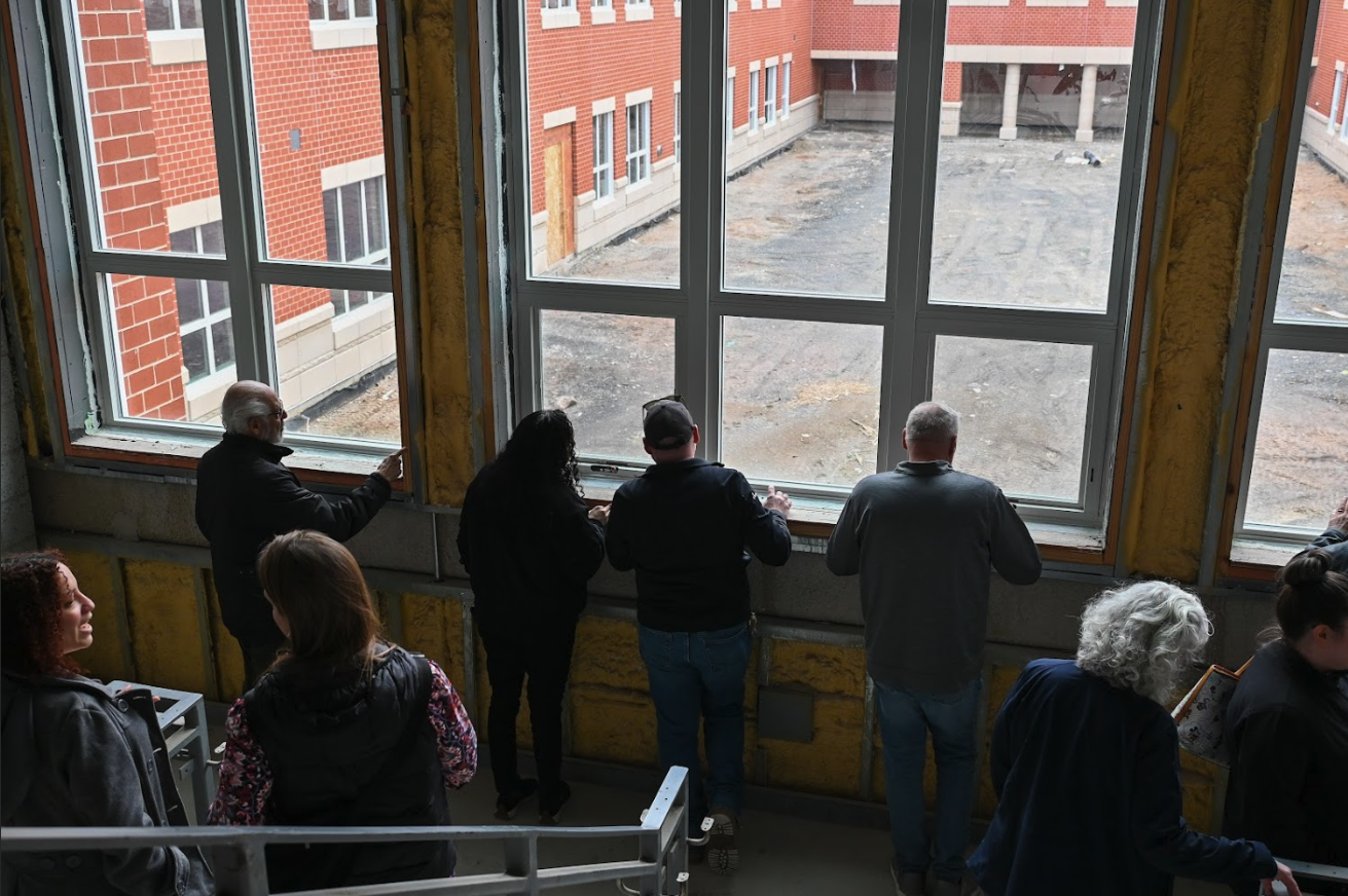 people looking out window of building under construction