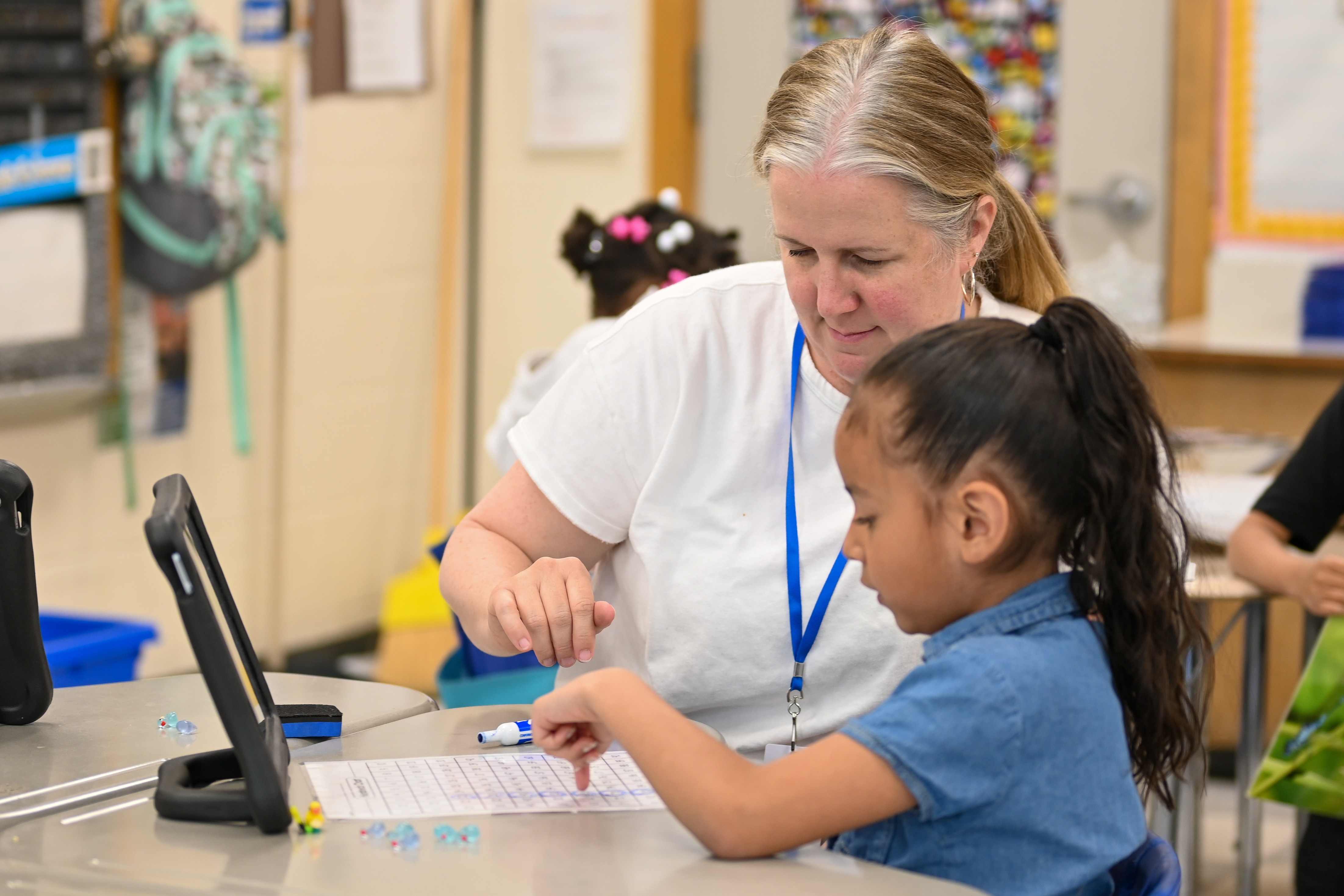 A teacher helping a student with an assignment at a table
