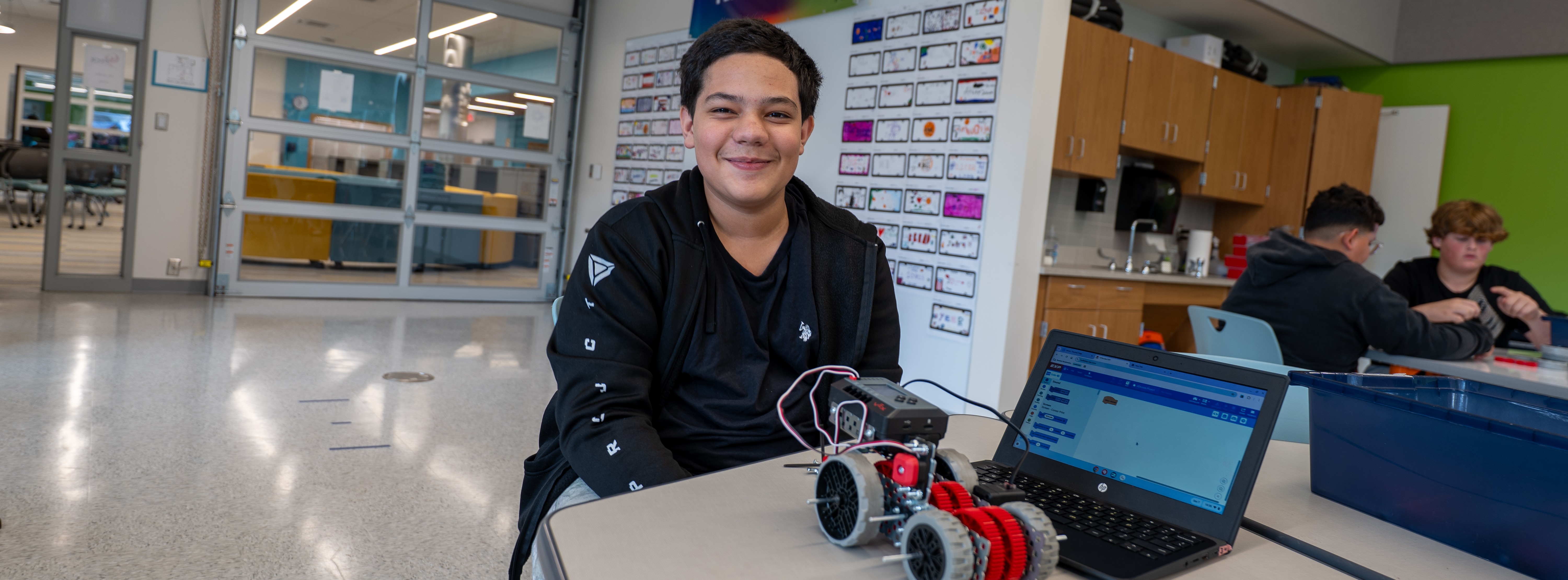 student displaying remote car on a desk hooked up to a computer