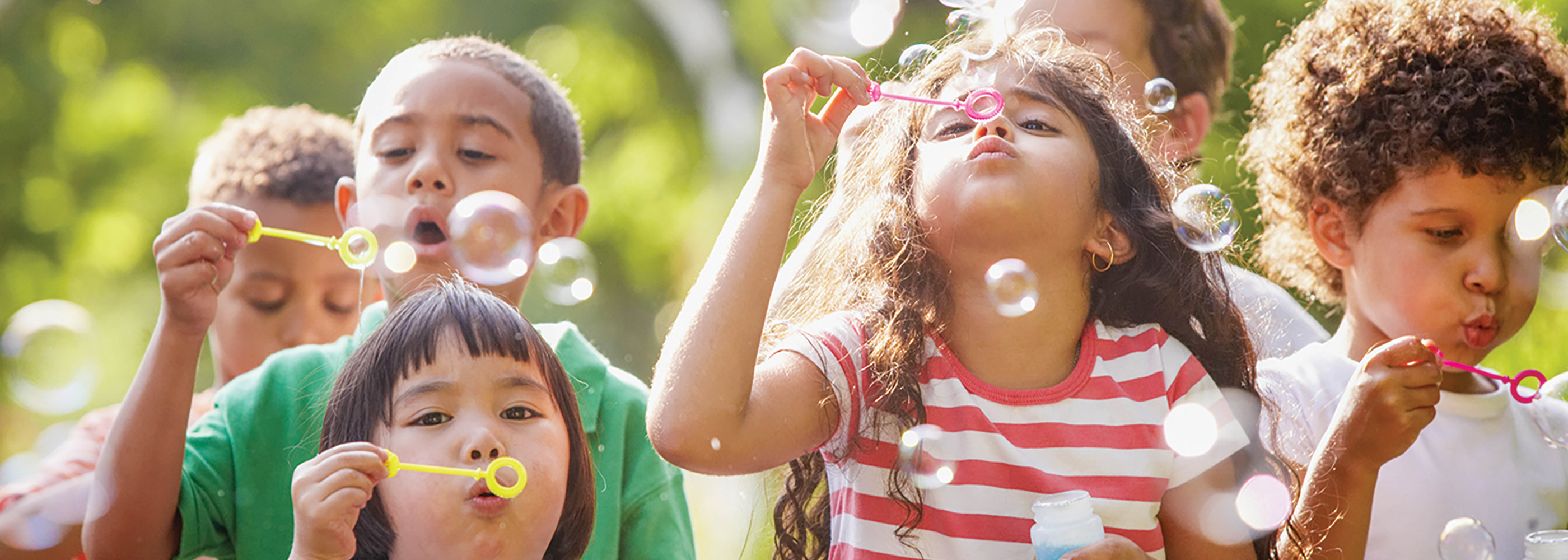 Multi-racial kids outside blowing bubbles