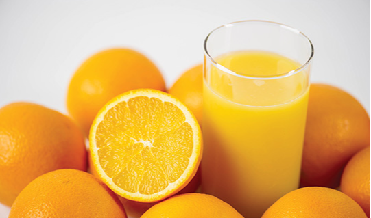 Photo: Glass of orange juice surrounded by oranges