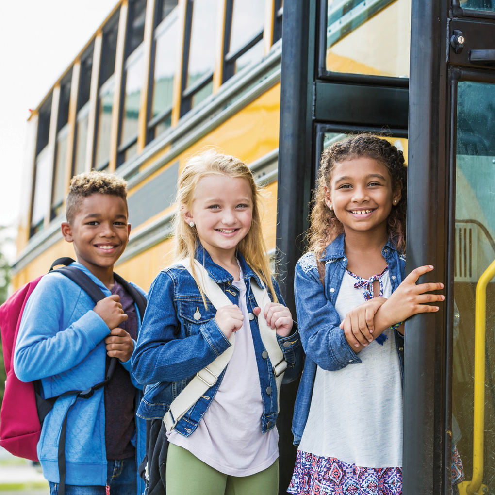 Three students ready to climb on a school bus