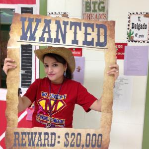 A staff member posing with a Wanted sign around her face