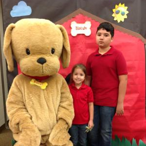 Two students posing with a human sized dog character